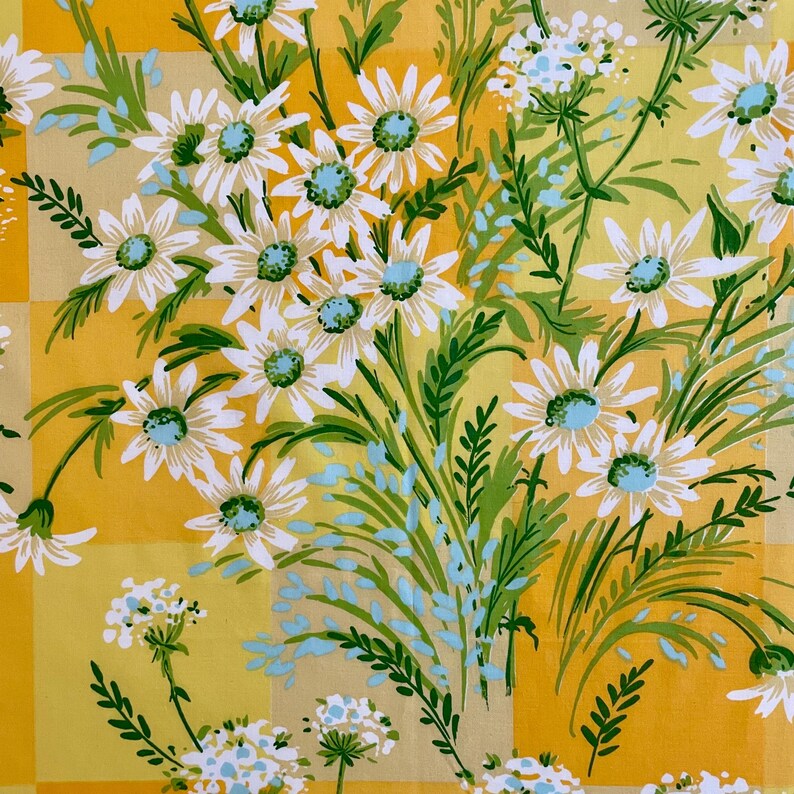 Puede incluir: Una tela a cuadros amarilla y blanca con un patr&oacute;n floral de margaritas blancas con centros azules y hojas verdes. La tela tiene un estilo vintage.