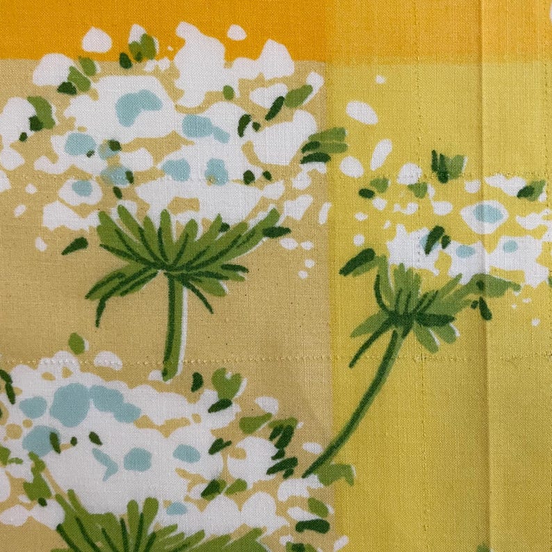 Puede incluir: Tela amarilla y blanca con un patr&oacute;n floral. Las flores son blancas con tallos y hojas verdes. La tela tiene un patr&oacute;n a cuadros.