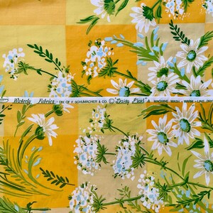 Puede incluir: Tela floral amarilla y blanca con un patr&oacute;n a cuadros. La tela tiene una etiqueta que dice "Waverly Fabrics - Div. of F. Schumacher & Co. Daisy Plaid" e instrucciones para lavar y secar.