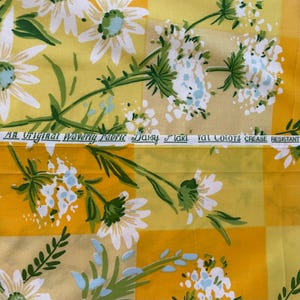 Puede incluir: Tela floral amarilla y blanca con una etiqueta que dice "An Original Waverly Fabric Daisy Field Val Colors Crease Resistant".