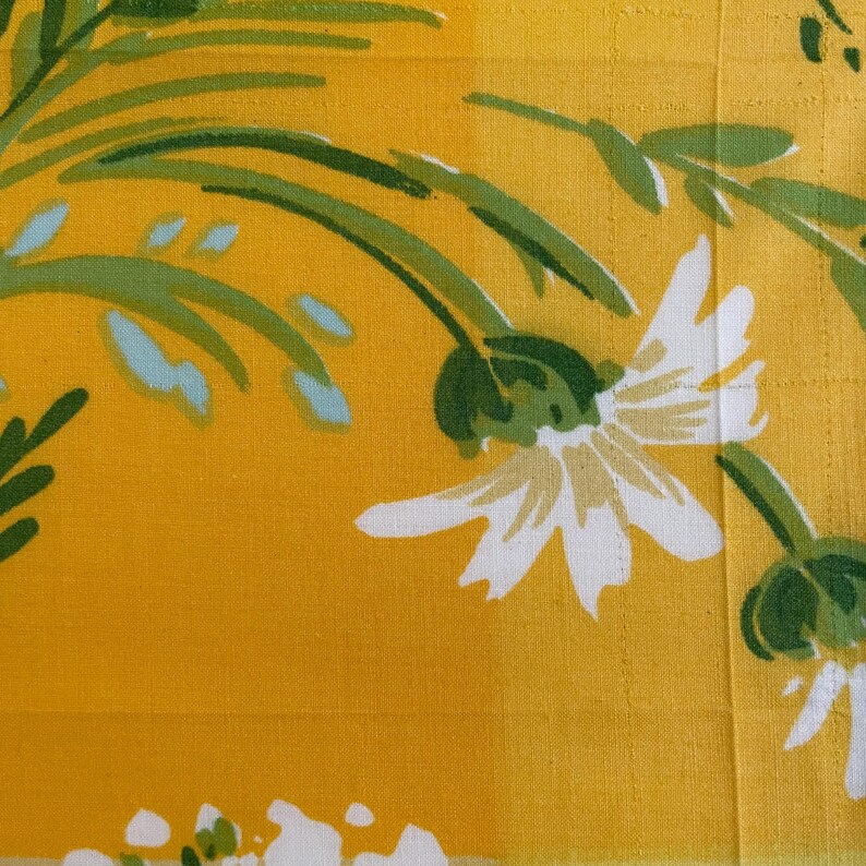 Puede incluir: Tela amarilla con un patr&oacute;n floral blanco. Las flores tienen un centro verde y p&eacute;talos blancos. El fondo es de color amarillo s&oacute;lido.