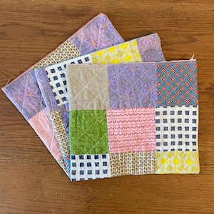 May include: A patchwork quilt with a variety of floral and geometric patterns in shades of pink, purple, yellow, green, and blue.