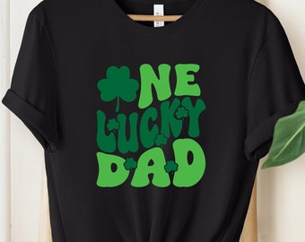 May include: Black t-shirt with a green shamrock and the text "One Lucky Dad" in a retro font.