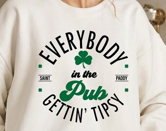 May include: Cream-colored sweatshirt with the text "EVERYBODY in the Pub GETTIN' TIPSY" in black and green. A green shamrock is centered above the word "Pub". The words "SAINT" and "PADDY" are on either side of the text.