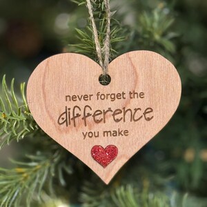 May include: Wooden heart-shaped ornament with the text "never forget the difference you make" and a red glitter heart.
