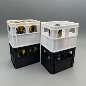 Könnte beinhalten: Zwei Plastikkisten, eine weiße und eine schwarze, übereinander gestapelt. Die obere Kiste ist weiß und die untere Kiste ist schwarz. Die Kisten sind für Batterien konzipiert. Die obere Kiste ist mit Batterien gefüllt.