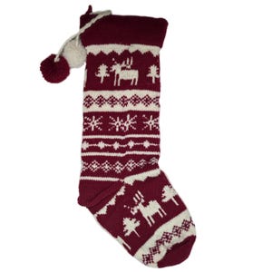 May include: A red and white knitted Christmas stocking with a white pom-pom on top. The stocking features a white reindeer and snowflake pattern.
