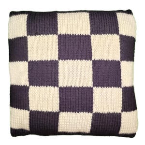 May include: A square-shaped pillow with a checkered pattern in shades of purple and cream. The pillow is made of knitted fabric.