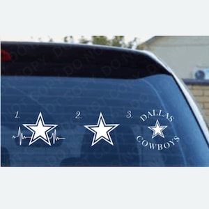Op de afbeelding: Drie witte sterstickers op een autoruit. De eerste heeft een hartslaglijn, de tweede is een eenvoudige ster en de derde heeft de woorden "DALLAS COWBOYS" rond de ster.