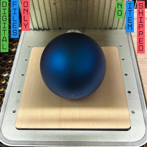 Puede incluir: Un adorno navideño azul sobre una base de madera. El adorno es redondo y liso. La base es de color marrón claro y tiene una forma rectangular. El texto "ONLY DIGITAL FILES" es visible en la imagen.