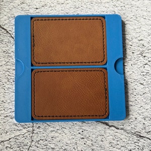 May include: A blue plastic card holder with two brown leather card slots. The card holder has a stitched edge.