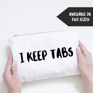 May include: White canvas zippered pouch with the text "I KEEP TABS" in black brush script lettering. Available in two sizes.
