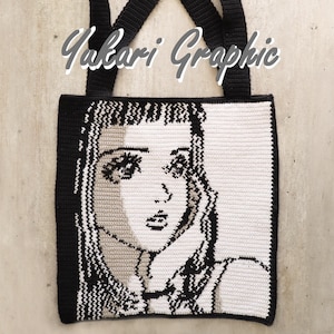 May include: Crochet tote bag in black and white, depicting a woman's face in a pop art style. The bag has black straps and trim, with the text "Yukari Graphic" across the top.