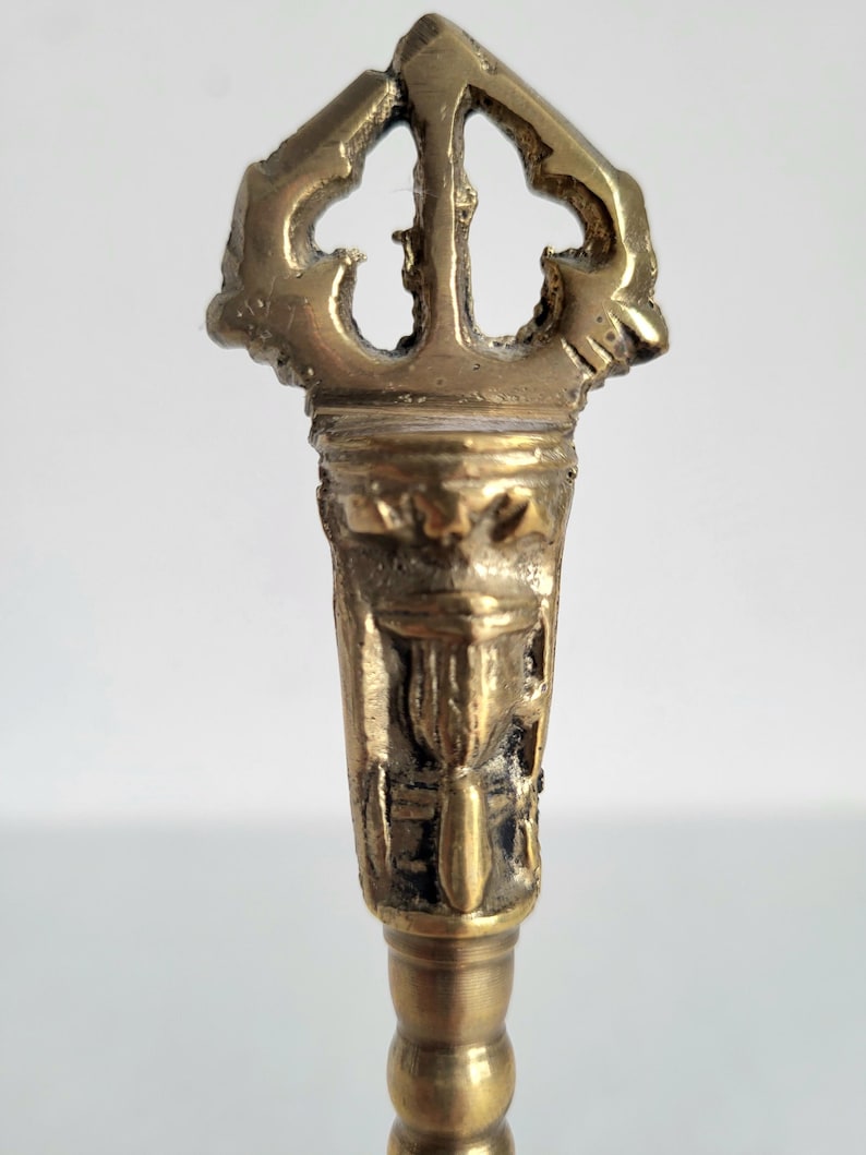 May include: A detailed close-up of a brass key with an ornate, openwork design at the top. The key has a textured surface and a decorative handle. The key is a vintage item.