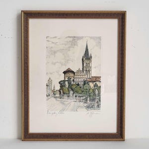 May include: Framed print of a European castle with a tall tower, set on a hill with trees and a road. The print is in a gold-coloured frame. The print has the text "Konigsberg Schloss" and a signature.