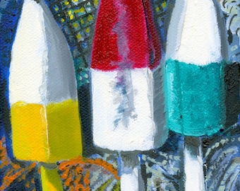 May include: Three colorful, wooden lobster buoys hanging from a rope. The buoys are painted in red, white, and yellow, and blue and white. The buoys are hanging against a dark blue and gray background.