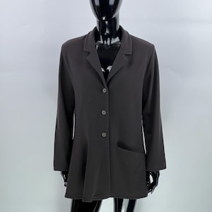 May include: A dark brown blazer with long sleeves, a notched collar, and three buttons. The blazer features a single pocket and a flared peplum hem. The garment is displayed on a black mannequin against a white background.