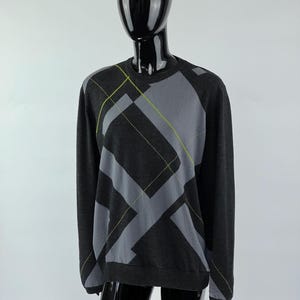 May include: A black sweater with a grey and green geometric pattern.