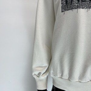 May include: Cream-colored sweatshirt with the word "FALC" in a textured, black font across the chest. The sweatshirt has long sleeves with ribbed cuffs and a ribbed hem. The fabric appears to be a soft, comfortable material.