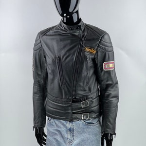 May include: Black leather motorcycle jacket with a zipper closure, two front pockets, and a Condor patch on the left sleeve. The jacket has a belt with two buckles at the waist.