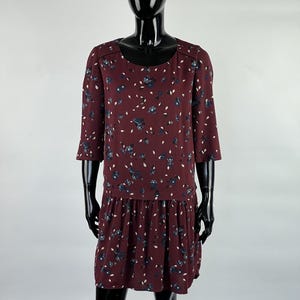 May include: A maroon floral print dress with a gathered skirt and 3/4 sleeves.