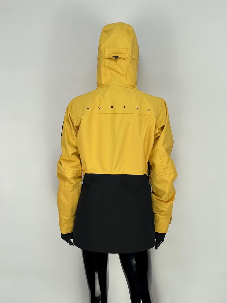 May include: Yellow and black hooded jacket with the word "MONTEC" printed across the back. The jacket has a yellow upper section and a black lower section. The jacket has a hood and long sleeves.