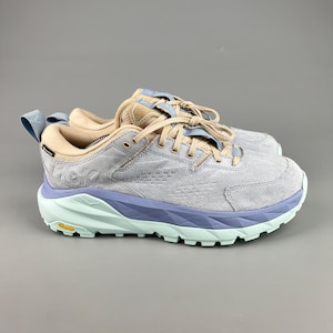 May include: A pair of gray suede athletic shoes with light blue and mint green accents. The shoes have a thick sole and are laced up. The brand name is visible on the side of the shoe.