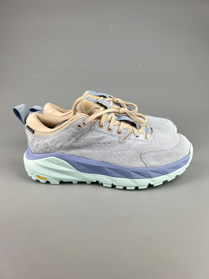 May include: A pair of gray suede athletic shoes with light blue and mint green accents. The shoes have a thick sole and are laced up. The brand name is visible on the side of the shoe.