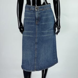 May include: A dark blue denim skirt with a straight cut and a slightly curved hemline.