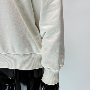 May include: Cream-colored sweatshirt with ribbed cuffs and hem. The long sleeves are gathered at the wrist. The fabric has a textured appearance. The sweatshirt is displayed on a black mannequin.