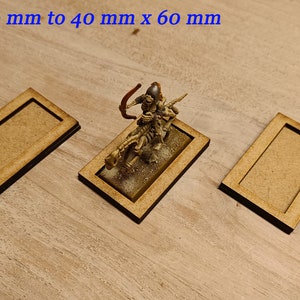 May include: Three wooden bases for miniature figures, measuring 25 mm x 50 mm to 40 mm x 60 mm. The bases are made of light brown wood and have a raised edge.