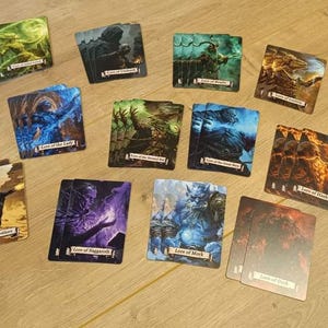 Könnte beinhalten: Eine Sammlung rechteckiger Spielkarten mit Fantasy-Illustrationen und Textbeschriftungen wie Lore of Beasts, Lore of Fire, Lore of Metal, Lore of Light, Lore of Heavens, Lore of Life, Lore of Death, Lore of Shadow und Lore of Naggoroth.