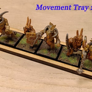Puede incluir: Una bandeja de movimiento de madera para figuras en miniatura, con cinco espacios cuadrados de 25 mm. La bandeja est&aacute; hecha de madera y tiene un acabado marr&oacute;n oscuro. La bandeja est&aacute; etiquetada "Movement Tray 25 mm" y "5 x 1".