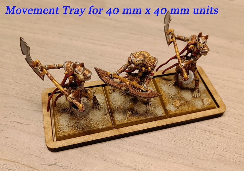 Puede incluir: Una bandeja de movimiento de madera para unidades de 40 mm x 40 mm. La bandeja tiene tres compartimentos, cada uno con una base pintada de color arena. Tres figuras en miniatura est&aacute;n de pie en la bandeja, cada una con un arma diferente.