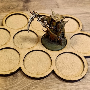 Puede incluir: Una bandeja de exhibici&oacute;n de figuras en miniatura de madera con ocho recortes circulares. Una figura en miniatura detallada con una guada&ntilde;a se coloca en la bandeja. La figura est&aacute; pintada en tonos de verde, marr&oacute;n y plata. La bandeja es de madera marr&oacute;n claro.