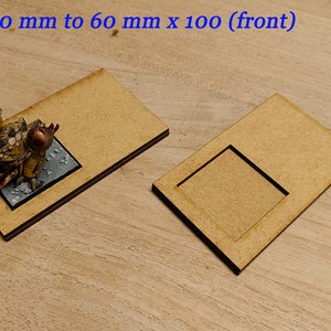 May include: Two wooden bases for miniature figures. The smaller base is 40 mm x 40 mm and the larger base is 60 mm x 100 mm. The bases are made of light brown wood and have a slightly textured surface.