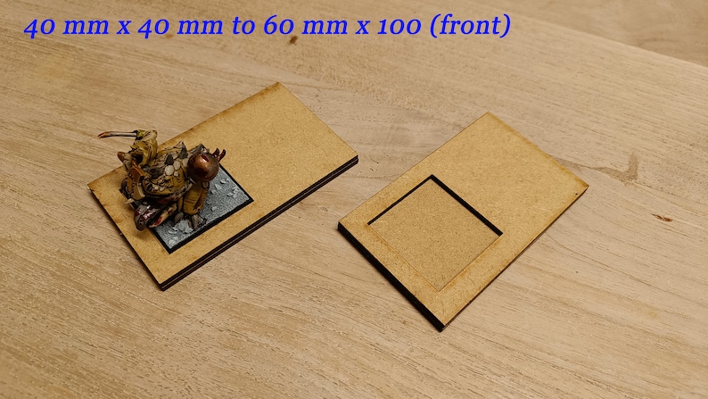 May include: Two wooden bases for miniature figures. The smaller base is 40 mm x 40 mm and the larger base is 60 mm x 100 mm. The bases are made of light brown wood and have a slightly textured surface.