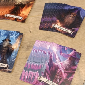Op de afbeelding: Een set van negen kaarten met verschillende soorten magie, waaronder Battle Magic, Demonology, Elementalism, Illusion en Necromancy. Elke kaart heeft een unieke illustratie van een tovenaar die een spreuk uitspreekt.