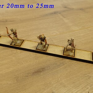 May include: A line of six miniature skeletal figures holding bows and arrows, standing on a wooden base. The base is labelled "Open Order 20mm to 25mm Line".