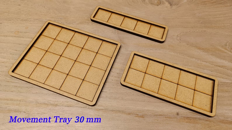 Puede incluir: Tres bandejas de madera con un patr&oacute;n de cuadr&iacute;cula. La bandeja m&aacute;s grande es cuadrada y tiene 25 cuadrados. Las otras dos bandejas son rectangulares y tienen 12 cuadrados cada una. El texto "Movement Tray 30 mm" est&aacute; impreso debajo de las bandejas.