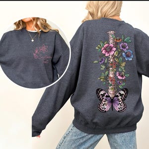 a woman wearing a sweatshirt with a butterfly and flowers on it