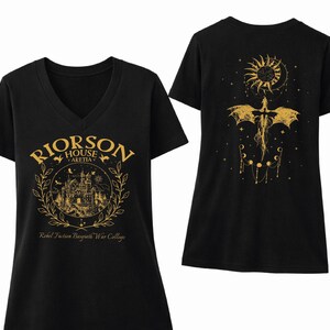 a black t-shirt with a gold design on the front and back. The front design includes a castle and a dragon, while the back design features a sun and a moon. The text on the t-shirt reads "Rierson House Aketia Rebel Fusion Basalt War College".