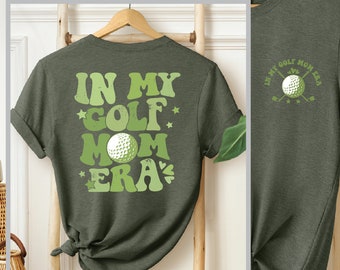 May include: Green t-shirt with the text "In My Golf Mom Era" in a retro font with a golf ball graphic. The back of the shirt has a smaller graphic of a golf ball with crossed golf clubs and the text "In My Golf Mom Era".