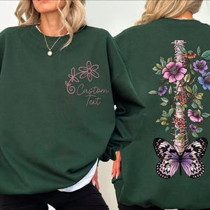 a woman wearing a green sweatshirt with butterflies on it