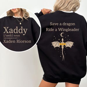 a woman wearing a black sweatshirt with a dragon design and text printed on the back.