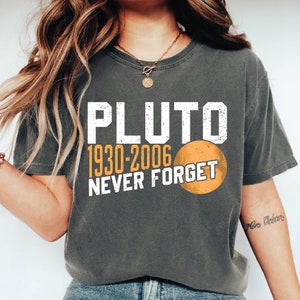 May include: A gray t-shirt with a white graphic that says "Pluto 1930-2006 Never Forget" and a stylized image of Pluto.