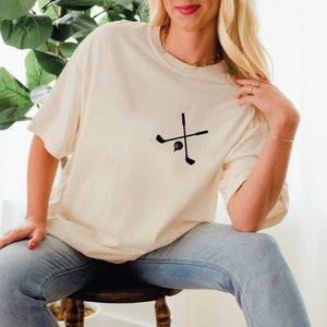 a woman sitting on a stool wearing a t - shirt with a cross on it