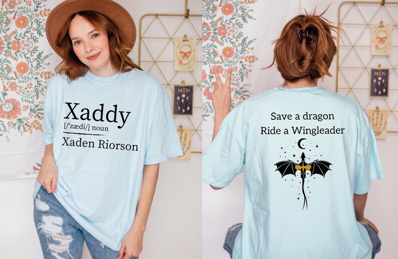a woman wearing a light blue t-shirt with a dragon design and text on the back.