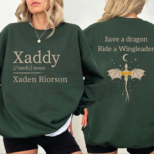 A woman wearing a green sweatshirt with text and graphics on the back.