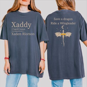 A woman wearing a blue t-shirt with text and a graphic on the back.